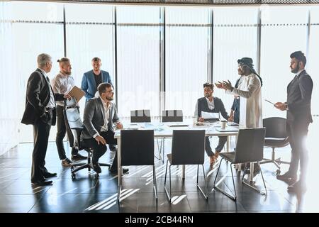 Multirassische Geschäftsleute diskutieren Negation im Büro mit Panoramafenster. Kommerzielle Konversation Stockfoto