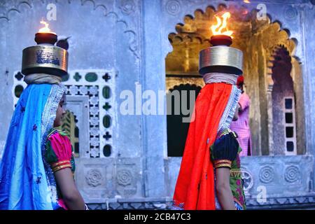 Udaipur, Indien - 24. Mai 2013: Zwei indische Frauen in Saree mit irdenen Glas auf Feuer balancieren auf dem Kopf beim Tanzen Stockfoto