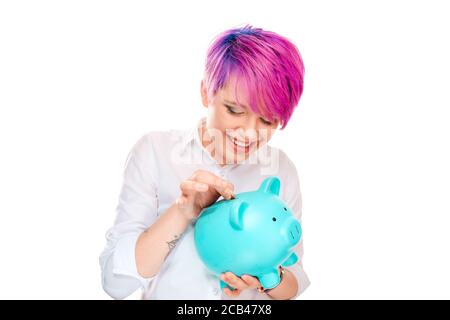 Frau, die Münze in ein Sparschwein auf weißem Hintergrund isoliert. Millennial-Modell mit rosa magentafarbenen Haaren. Einsparkonzept Stockfoto