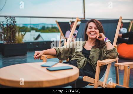 Junge wunderschöne Frau sitzt in gemütlichen Stuhl im Café im Freien Stockfoto