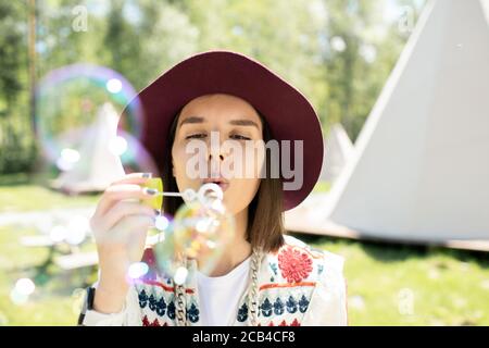 Hübsches Mädchen, das gegen Zelte und Seifenblasen steht Während Sie Spaß im Freien haben Stockfoto
