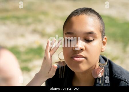 Nahaufnahme einer nicht erkennbaren Frau, die Glitzer-Make-up in Schwarz aufsetzt Mädchen im Freien Stockfoto