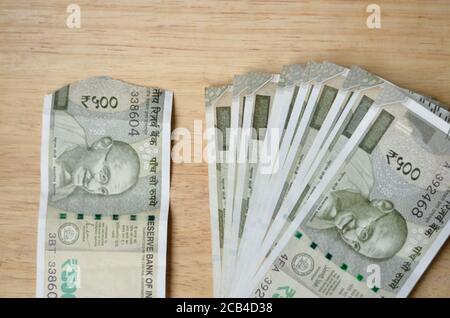 Eine zerrissene neue RS 500 Rupien Indische Währung Noten neben einem Bündel vor einem hölzernen Bokeh Hintergrund gehalten. Stockfoto