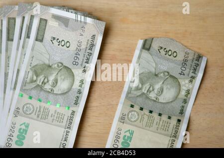Eine zerrissene neue RS 500 Rupien Indische Währung Noten neben einem knackigen vor einem hölzernen Bokeh Hintergrund gehalten. Stockfoto