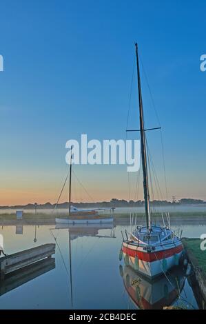 Potter Heigham, Norfolk .Broads, Segelboote auf dem Fluss Thurne an einem nebligen Sommermorgen festgemacht Stockfoto