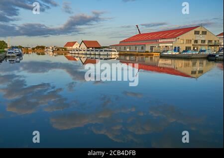 Bootsschuppen und Bootsverleih bei Potter Heigham spiegelt sich im Fluss Thurne, Norfolk frühen Sommermorgen Stockfoto