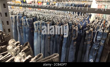 Jeans hängen in einem Laden an Kleiderbügeln in einer Reihe. Nahaufnahme. Breit Stockfoto