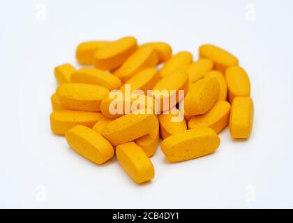 Große orange Pillen auf weißem Hintergrund. Ovale Tabletten aus Kalzium und Magnesium. Nahrungsergänzungsmittel in Kapselform. Stockfoto