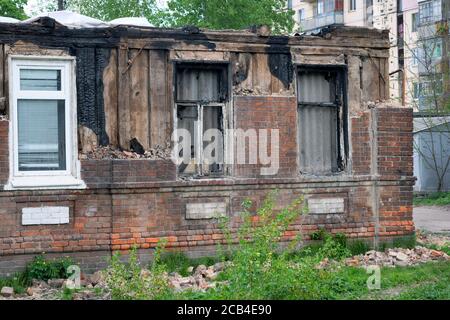 Teilweise abgebranntes Gebäude ohne Dach. Ein altes einstöckiges Haus nach dem Brand. Ein altes Gebäude durch einen starken Brand beschädigt, verbrannte Fenster und coll Stockfoto