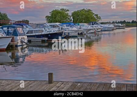 Potter Heigham, Norfolk Broads und Boote vertäuten in der Marina mit einem bunten Himmel im Wasser reflektiert. Stockfoto