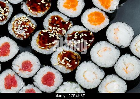 Japanisches Essen. Brötchen mit reifer Avocado, rotem Fisch, Lachs, frischem Reis mit Gemüse in Nori. Set mit Rollen Stockfoto