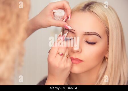 Ändern der Brauenform. Stylistin zeichnet die Augenbrauen mit dunklem Bleistift. Mikropigmentierung Arbeit Flow in einem Schönheitssalon. Frau mit ihrem Auge br Stockfoto