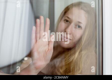 Die weibliche Hand auf dem Glas, die sich an das Fenster von der Traurigkeit in der Isolation während der Quarantäne der Epidemie des Coronavirus covid-19 lehnt, Nahaufnahme. Stockfoto