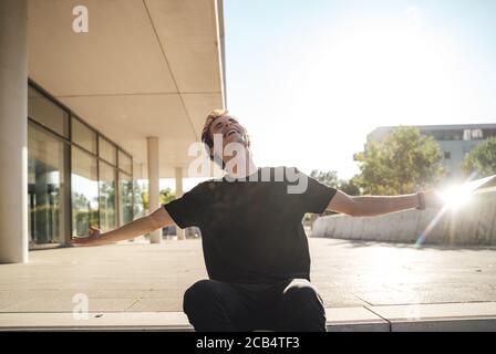 Erfolgreicher Geschäftsmann hält digitale Tablet sitzen Arme außerhalb des Büros ausgestreckt Stockfoto