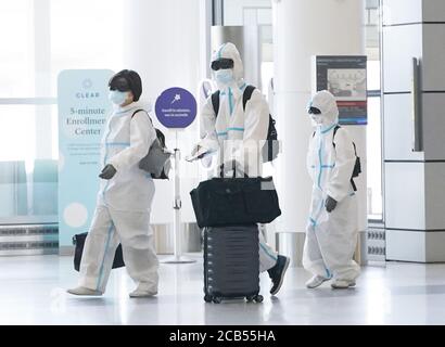 San Francisco, Usa. August 2020. Ein Mann, eine Frau und ein Kind gehen durch den Eingang zum Terminal 2 am San Francisco International Airport in Ganzkörperanzügen, Gesichtsmasken und Brillen, um am Montag, den 10. August 2020, das mögliche Fangen und Ausbreiten von COVID-19 in San Francisco zu verhindern. Foto von John Angelillo/UPI Kredit: UPI/Alamy Live Nachrichten Stockfoto