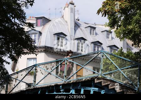 Paris, Frankreich. August 2020. Eine Frau geht auf einer Brücke des Saint-Martin-Kanals in Paris, Frankreich, 10. August 2020. Die Fälle der neuartigen Coronavirus-Infektion in Frankreich übertrafen am Montag 200,000, wobei 4,854 Neuinfektionen in den letzten drei Tagen bestätigt wurden. Die Gesamtzahl der bestätigten Fälle stieg auf 202,775 und 332 Cluster sind noch aktiv, nach den neuesten Daten des Gesundheitsministeriums veröffentlicht. Kredit: Gao Jing/Xinhua/Alamy Live Nachrichten Stockfoto