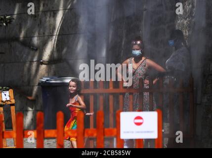 Paris, Frankreich. August 2020. Zwei Frauen beobachten, wie sich ein Mädchen unter einem Dampfbrunnen in Paris Plages, Frankreich, am 10. August 2020 abkühlt. Kredit: Gao Jing/Xinhua/Alamy Live Nachrichten Stockfoto