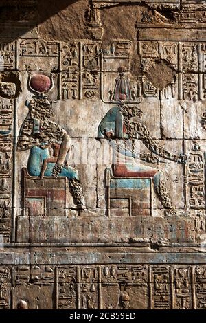 Ein graviertes Relief und Hieroglyphen am Tempel des Horus bei Edfu in Ägypten, das den gott Hathor (links) und Osiris (rechts) zeigt. Stockfoto