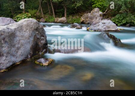 Langzeitbelichtung Fotografie von Wasser fließt über Felsen passiert groß Felsbrocken Stockfoto