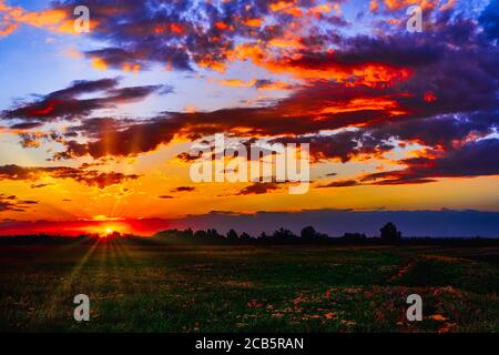 Helles Sonnenlicht, das durch die Wolken vor dem Hintergrund eines atemberaubenden Abendhimmels bei Sonnenuntergang scheint. Panorama, natürliche Komposition Stockfoto