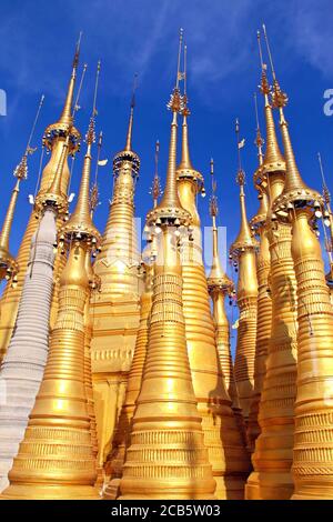 Goldene buddhistische Stupas mit Glocken auf dem Hintergrund des blauen Himmels mit Wolken bei Shwe Indein, Inle Seengebiet in Myanmar Stockfoto