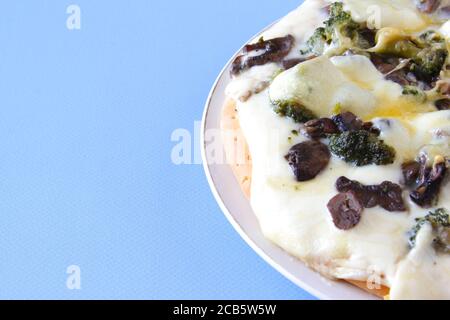 Vegetarische Pizza mit Brokkolli und Pilzen auf dem blauen Hintergrund. Speicherplatz kopieren. Draufsicht Stockfoto