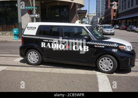 Ein maskierter Kabinenfahrer von Radio wird in seinem Taxi in Portland, Oregon, während eines pandemischen Sommers gesehen. Radio Cab wurde 1946 gegründet und war das erste Taxiunternehmen der Stadt. Stockfoto