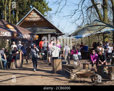 Tschechische Republik, Skalka, 7. April 2018: Gruppe von Menschen Männer Frau wartet in que in Holz Fast-Food-Stand und sitzt auf Picknick-Tischen, Waldbaum Stockfoto