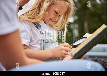 Ziemlich kleine Schulmädchen macht Hausaufgaben im Park Stockfoto