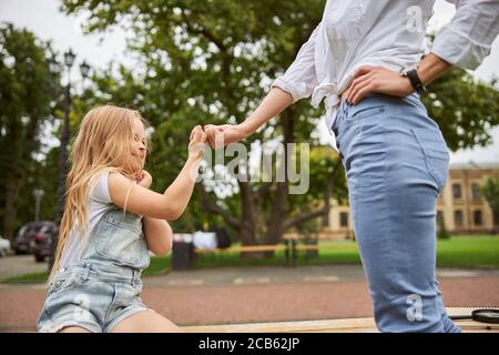 Erwachsene kaukasische Frau, die Frieden mit Tochter im Park macht Stockfoto