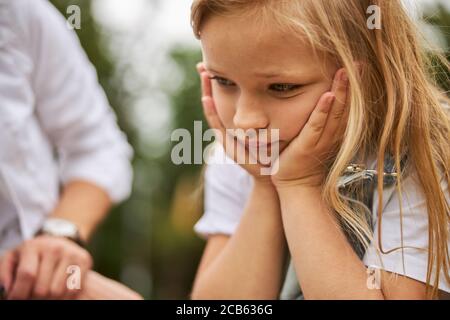 Trauriges Mädchen hält die Hände unter das Kinn Stockfoto