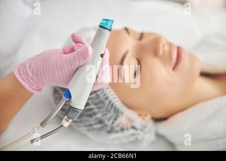 Ruhige junge Dame, die sich einer Hautbehandlung unterziehen Stockfoto