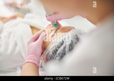 Junge kaukasische Frau, die sich einem dermatologischen Verfahren unterziehen Stockfoto