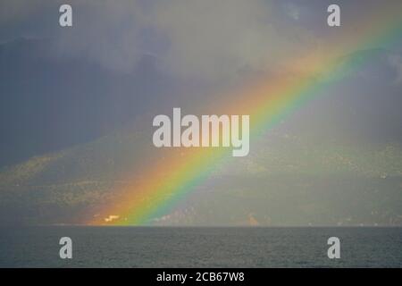 Regenbogen über dem Mittelmeer. Fotografiert in Poros ist ein kleines griechisches Inselpaar im südlichen Teil des Saronischen Golfs, Griechenland im November Stockfoto