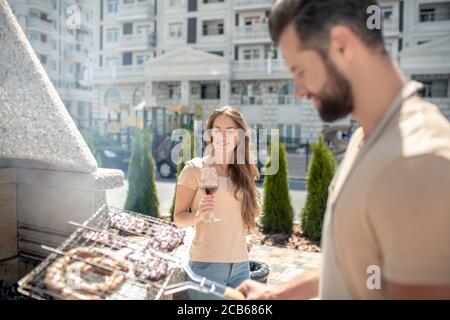 Junger Mann grillen Fleisch und suchen beteiligt Stockfoto