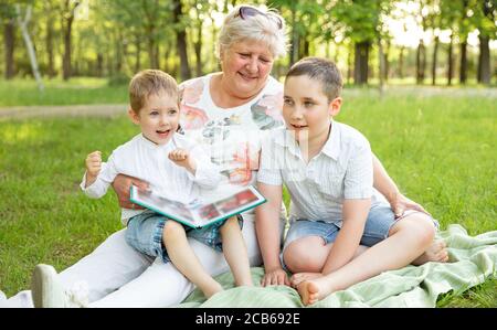 Kinder und Oma Spaß haben. Ältere Frau zeigt das Familienalbum Stockfoto