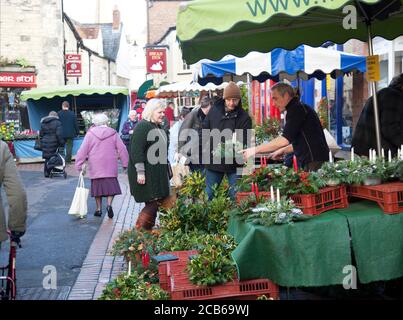 Einkäufer wählen Weihnachtsbäume Dekorationen Holly Beeren in einem Cotswold Famers Markt Stockfoto