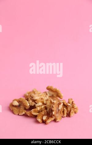 Vertikale Aufnahme eines Bündels von Walnüssen auf einem rosa Hintergrund Stockfoto