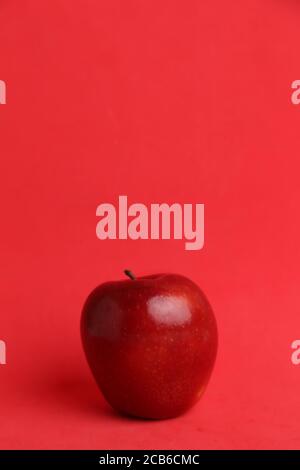 Vertikale Aufnahme eines ganzen roten Apfels isoliert auf einem Roter Hintergrund Stockfoto