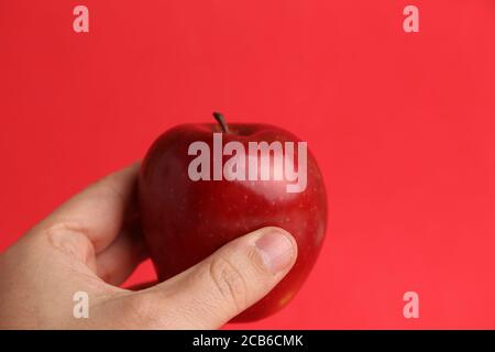 Person, die einen glänzenden reifen roten Apfel in der Hand hält Stockfoto