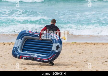 Ein Urlauber mit einem Schlauchboot auf Fistral; Beach in Newquay in Cornwall. Stockfoto