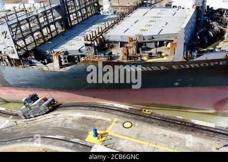 Elektrischer Schlepper oder Maultier führt in das Containerschiff Hansa Europa an die Miraflores Schleuse auf dem Panamakanal Stockfoto