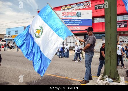 Guatemala-Stadt / Guatemala - 27. August 2015: Guatemaltekischer Mann, der während eines regierungsfeindlichen Protestes auf den Straßen eine große guatemaltekische Flagge schwenkt Stockfoto