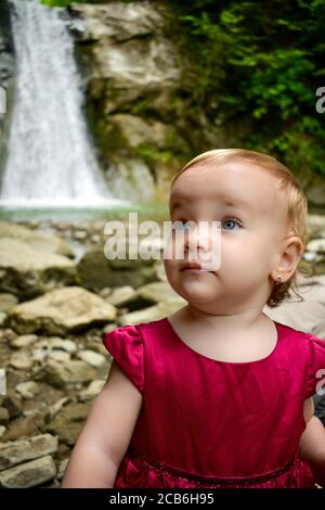 Baby Mädchen Porträt mit einem Wasserfall im Hintergrund Stockfoto