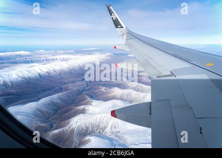 Luftaufnahme der schneebedeckten Bergketten im Winter von der Fenster eines Air New Zealand Fluges während des Fluges in Richtung Queenstown Stockfoto