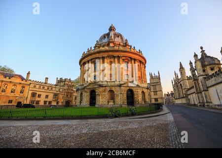 Die Radcliffe Kamera in Oxford bei Sonnenaufgang ohne Leute herum, früh am Morgen an einem klaren Tag mit blauem Himmel. Oxford, England, Großbritannien.
