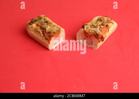 Nahaufnahme von zwei Stück Pizzabäse mit Wurst Auf einem roten Hintergrund Stockfoto