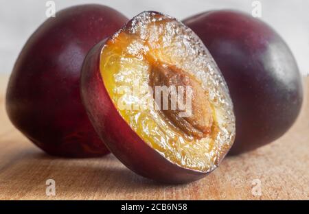 Zwei reife Pflaumen und eine halbe geschnittene Pflaume mit einem Stein Stockfoto