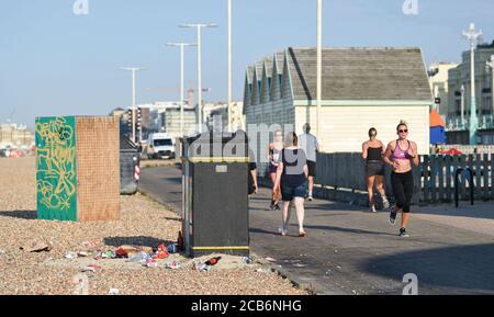 Brighton UK 11. August 2020 - Läufer kommen an einem überfließenden Abfalleimer an der Küste von Brighton vorbei, da die Temperaturen in Teilen des Südostens wieder weit über 30 Grad erreichen werden, während andere Teile des Landes von Gewittern heimgesucht werden: Kredit Simon Dack / Alamy Live Nachrichten Stockfoto