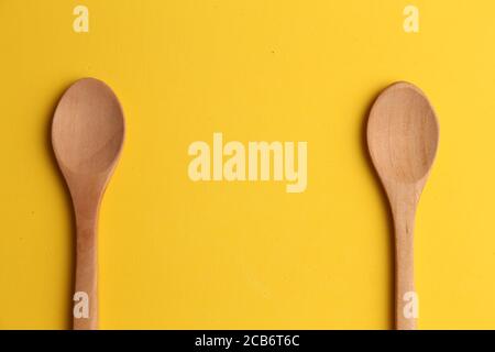 Nahaufnahme von zwei Holzlöffeln auf gelbem Hintergrund Stockfoto